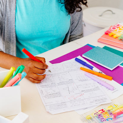 Teacher correcting students' papers at her desk with red color write fountain pen