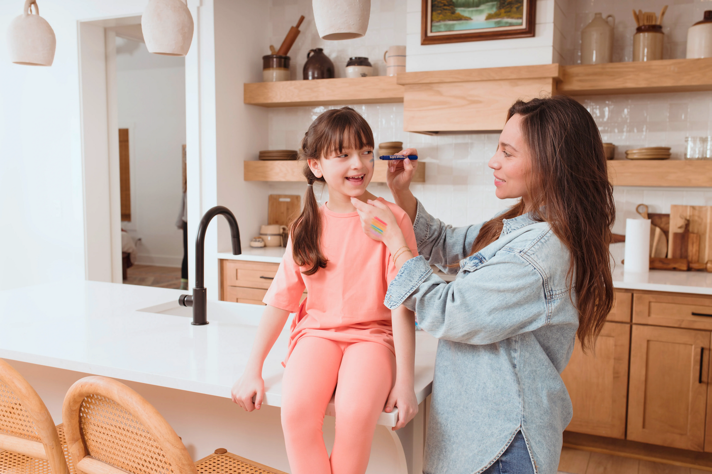 Woman drawing with OOLY Body Doodlers - Face & Body Crayon on little girl's face