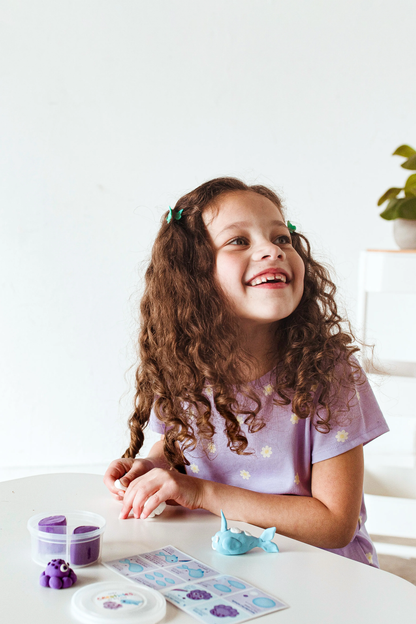 Girl looking up while making animals from OOLY Creatibles Mini Air Dry Clay Kit - Ocean BFFs