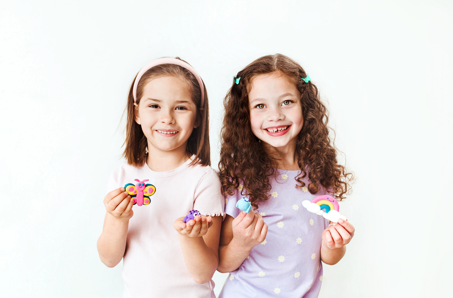 Two girls holding completed Girl building clay from OOLY Creatibles Mini Air Dry Clay Kit - Ocean and Rainbow BFFs