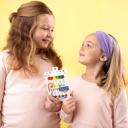 Two girls holding a set of Double Up! Double-Ended Markers with yellow background