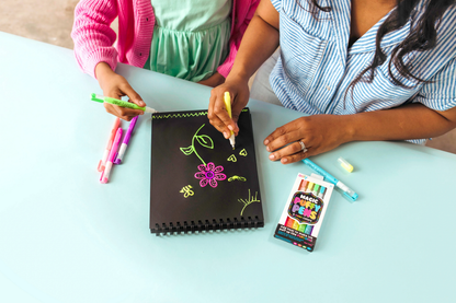 Couple coloring with OOLY Magic Puffy Neon Pens on black paper pad medium shot