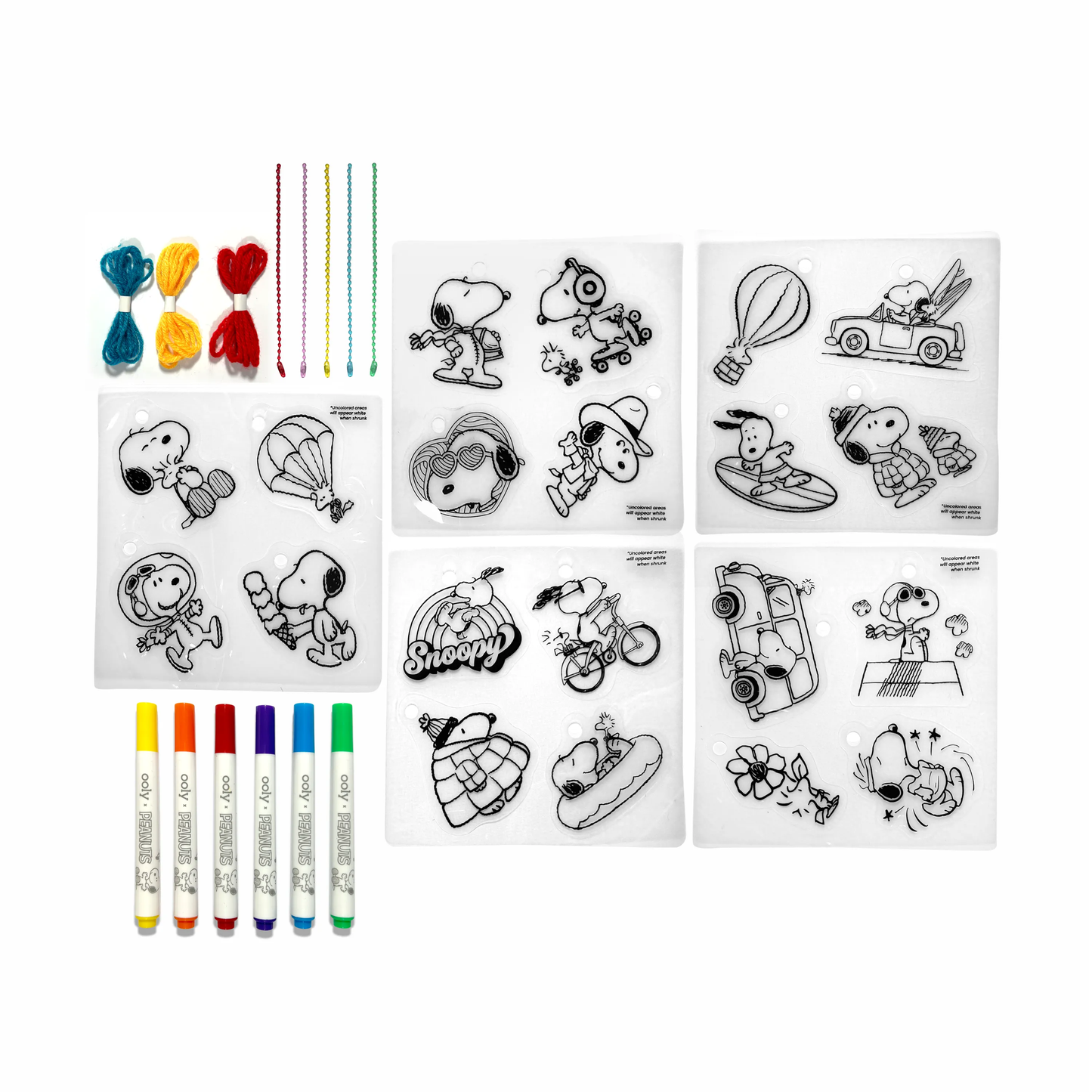 Contents of OOLY x Peanuts DIY Shrink Art Kit including cordage, beaded cords, markers and shrink sheets